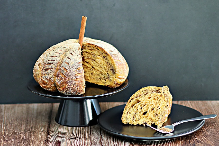 Pumpkin Shaped Pumpkin Spice Sourdough Bread with one piece cut out on a black plate with a fork