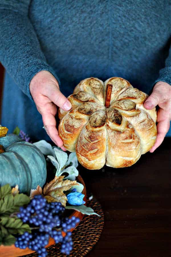 hands holding a pumpkin shaped pumpkin spice sourdough bread