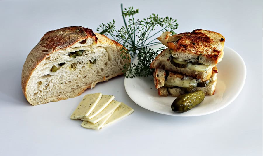 sourdough havarti and dill bread cut in half with dill pickles and havarti cheese from the Sour Strawberry Blog