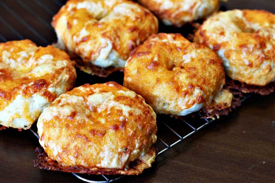 home made sourdough bagels with cheddar and asiago cheese topping on a cooling rack