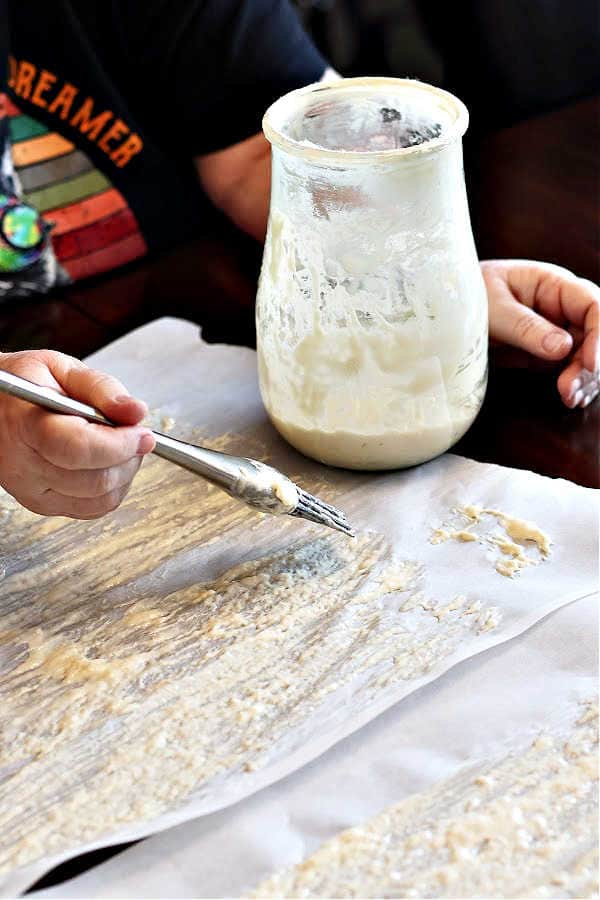 picture of painting sourdough starter onto a piece of parchment paper to dehydrate it