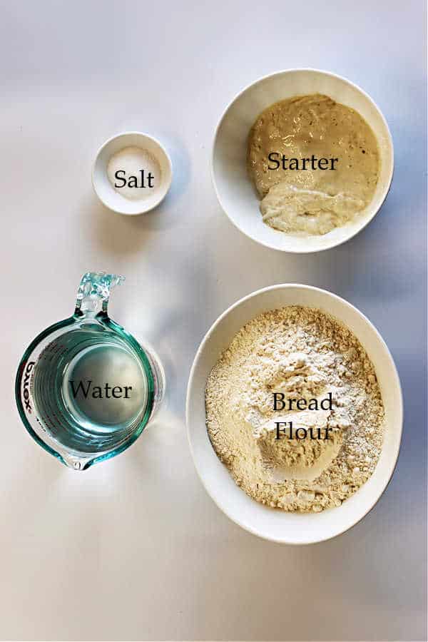 picture of 3 white bowls and a glass measuring cup filled with salt, starter, water and bread flour to make sourdough focaccia bread